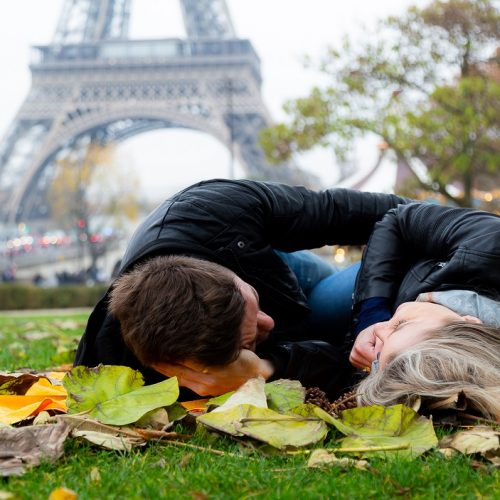 Ensaio na Torre Eiffel por fotografo brasileiro em Paris que registra casal deitado na grama no Trocadéro durante outono